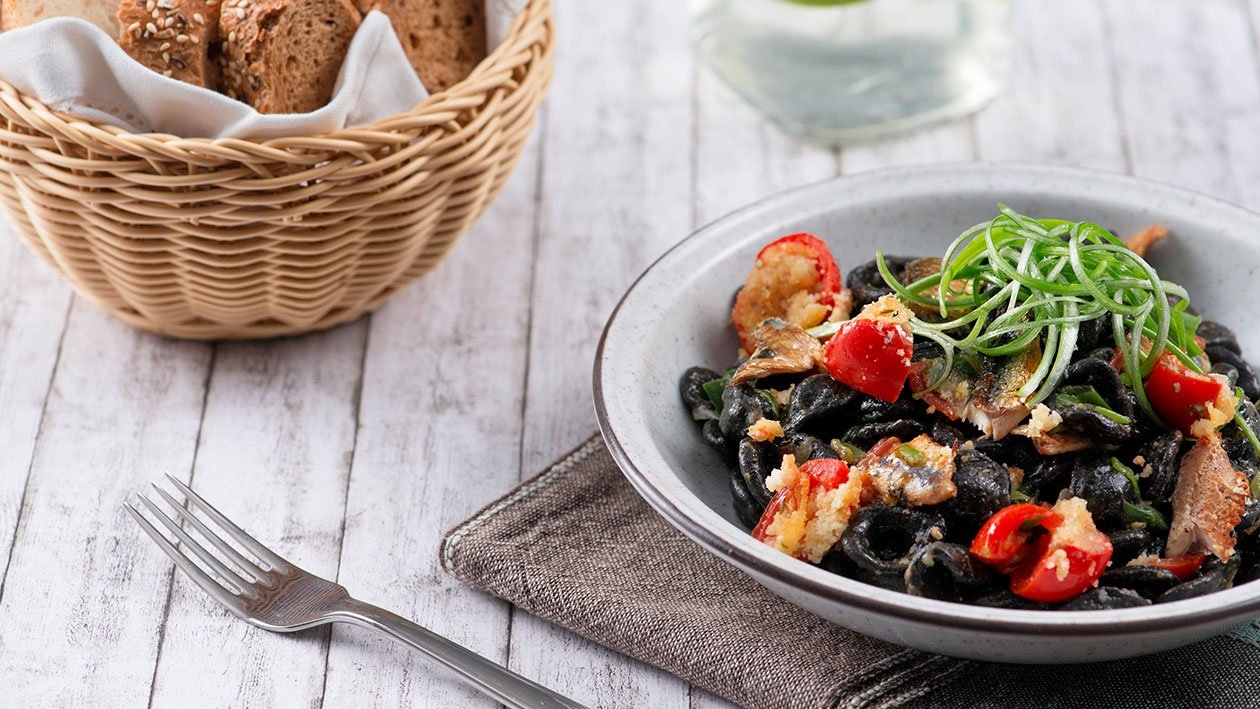 Orecchiette al nero con aringa affumicata, pomodorino gratinato e cipollotti – - Ricetta